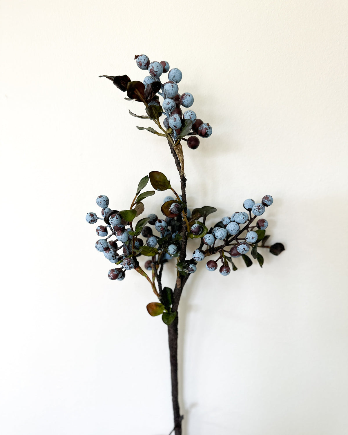 Artificial berry spray stem with mixed blue and dark berries and scattered green leaves