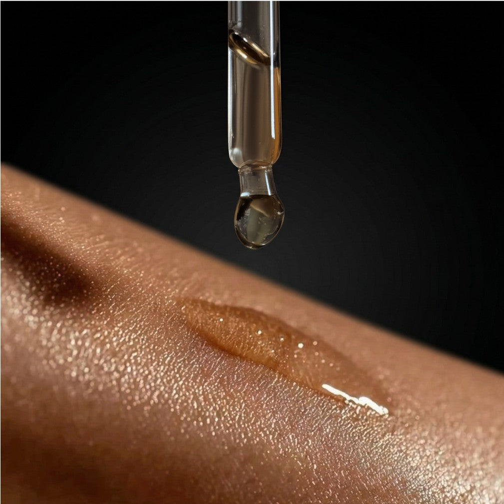 Body oil dropper dispensing a golden oil onto skin