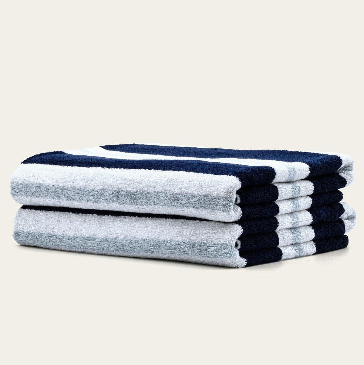 Stacked cotton beach towels with navy and white stripes and soft gray base