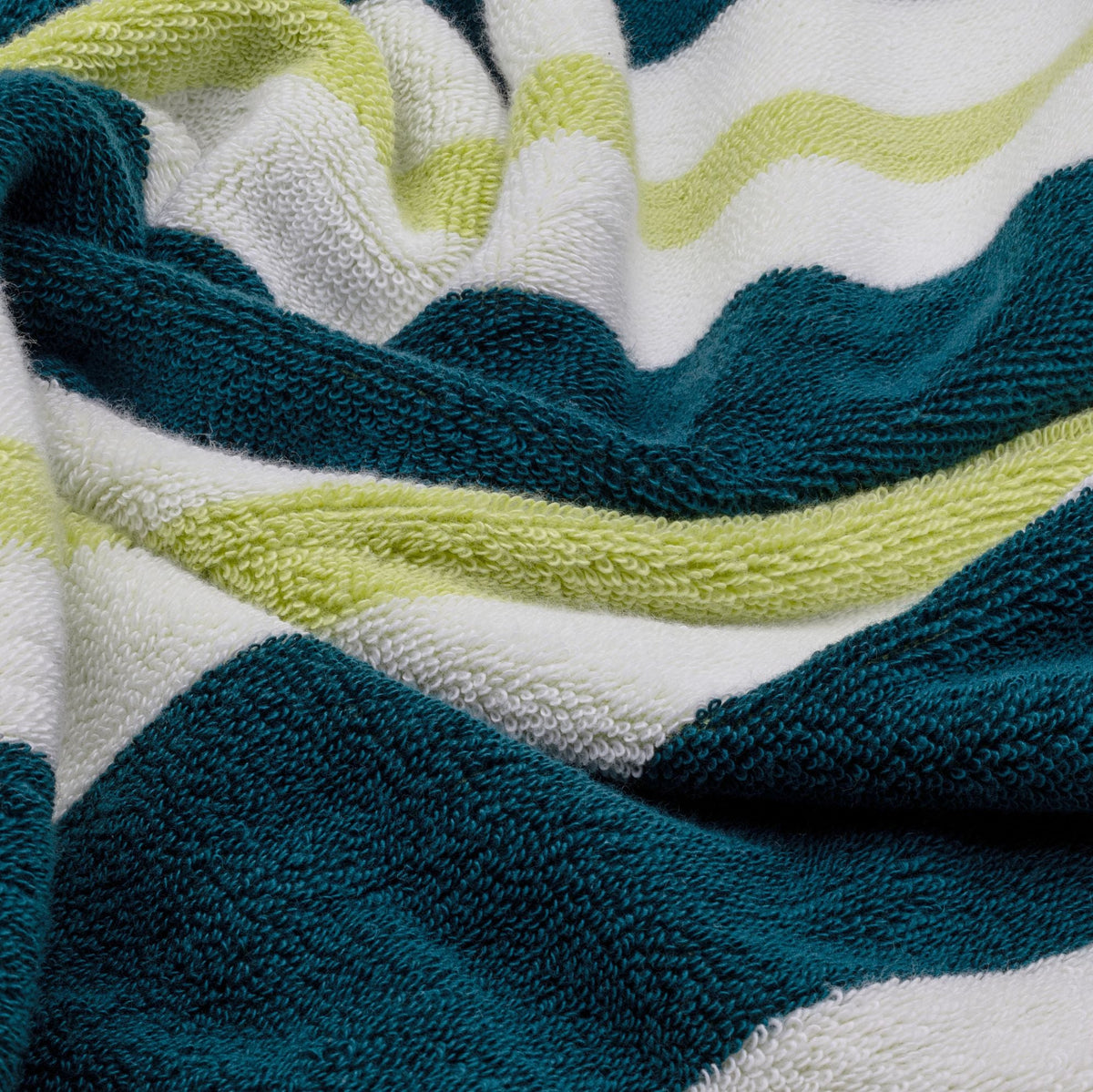 Close-up terry texture of teal, white, and lime striped cotton beach towel