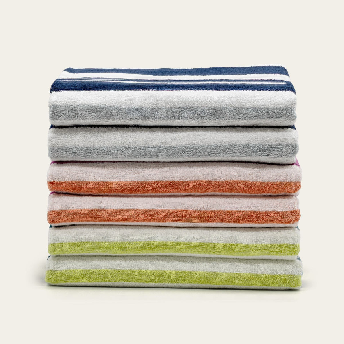 Stack of folded cotton beach towels in gray, orange, lime, and navy stripe