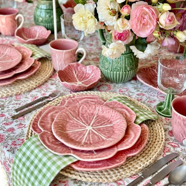 Pink cabbage-shaped bowls and plates arranged on a table.