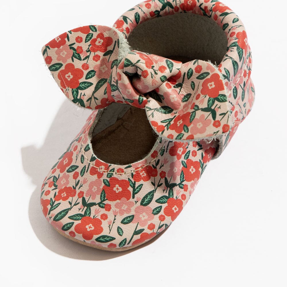 Floral baby shoe pair close-up with knotted bow and cushioned interior