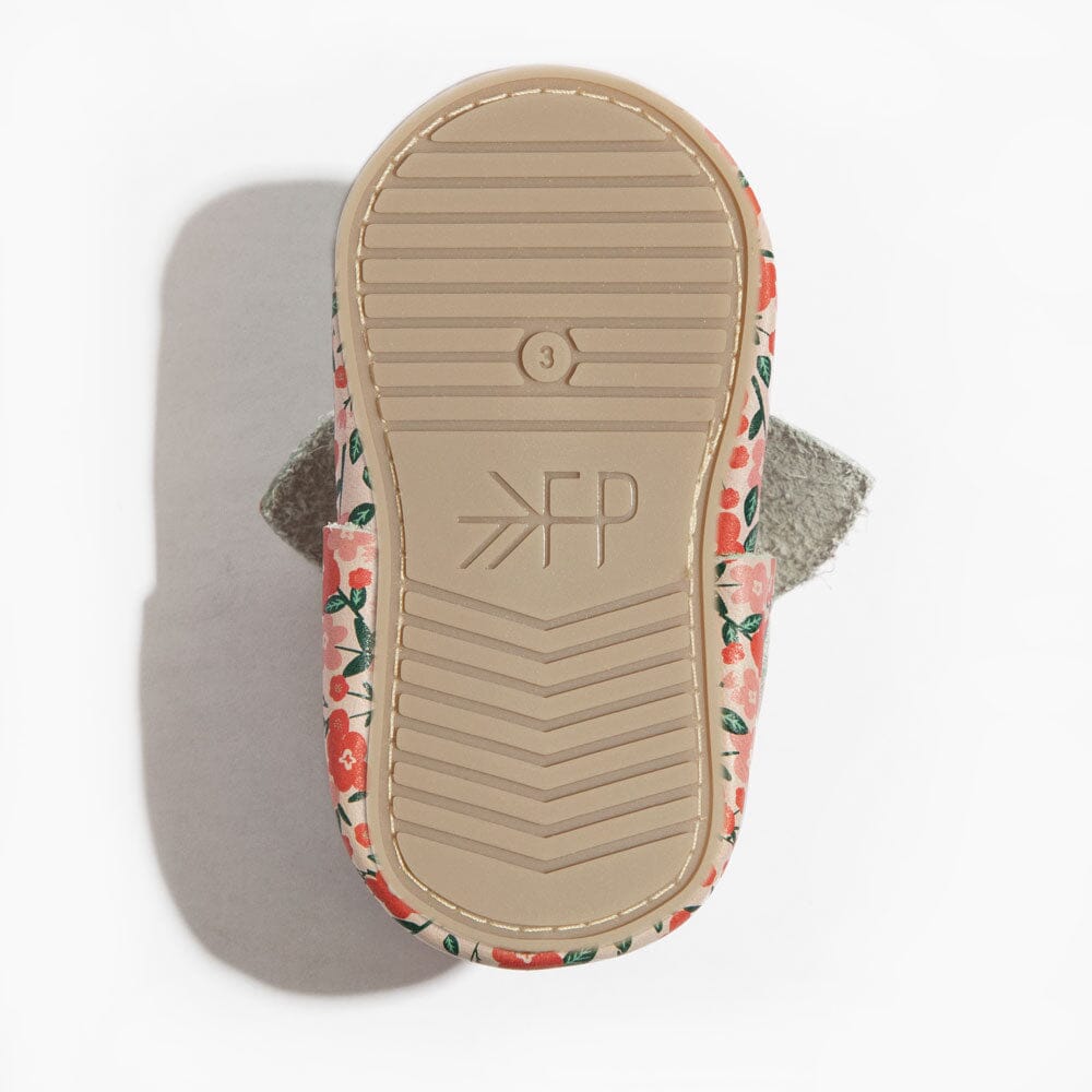 Underside view of floral baby shoes with textured tan rubber outsole