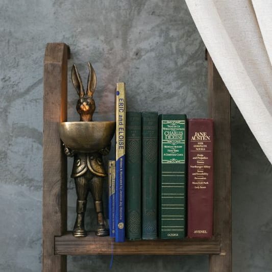 Brass gold hare candle holder bowl with hare figure on a wooden bookcase shelf