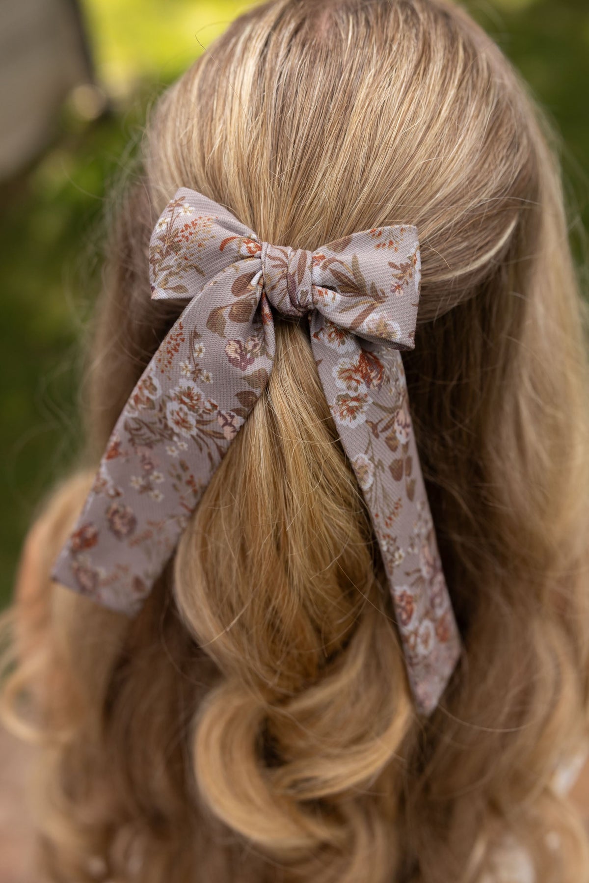 Floral lady hair bow tied on blonde hair with long dangling tails