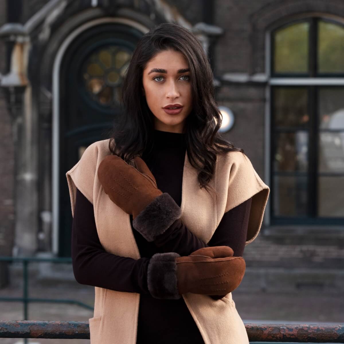Brown suede mittens with dark fur lining and cuffs, worn by model