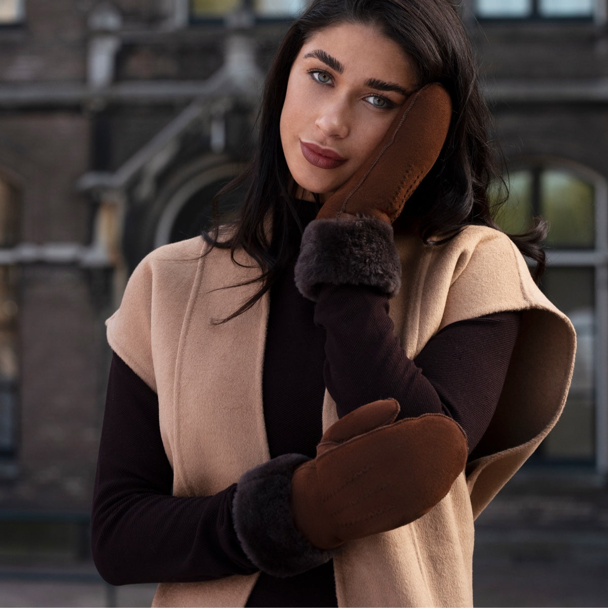 Brown suede mittens with dark fur cuffs, model holding hands together