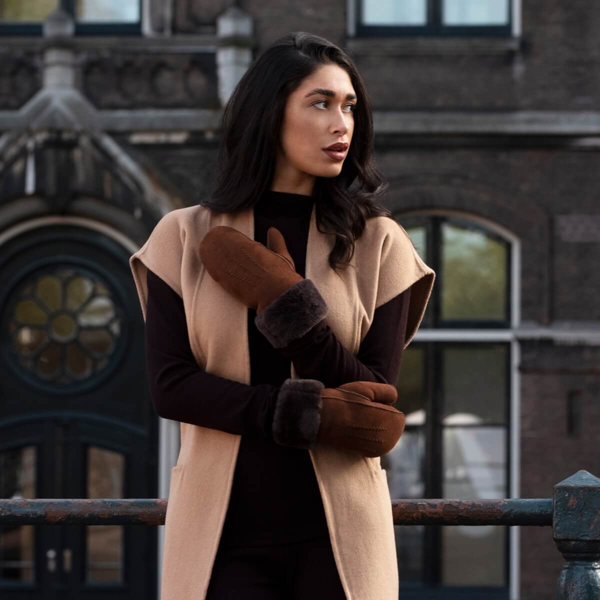 Brown suede mittens with dark fur lining, model wearing gloves