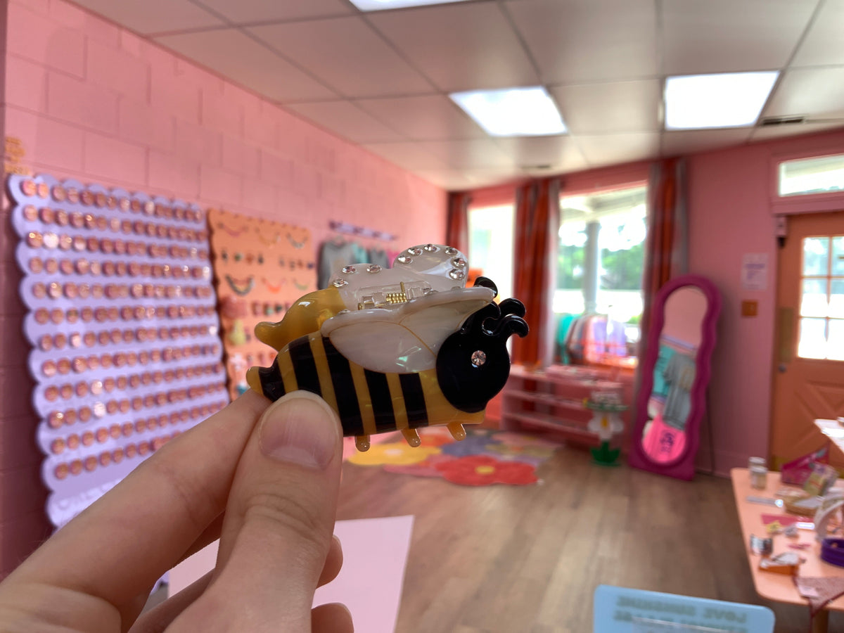 Pair of bee hair claws with yellow-black stripes and clear glitter wing tops