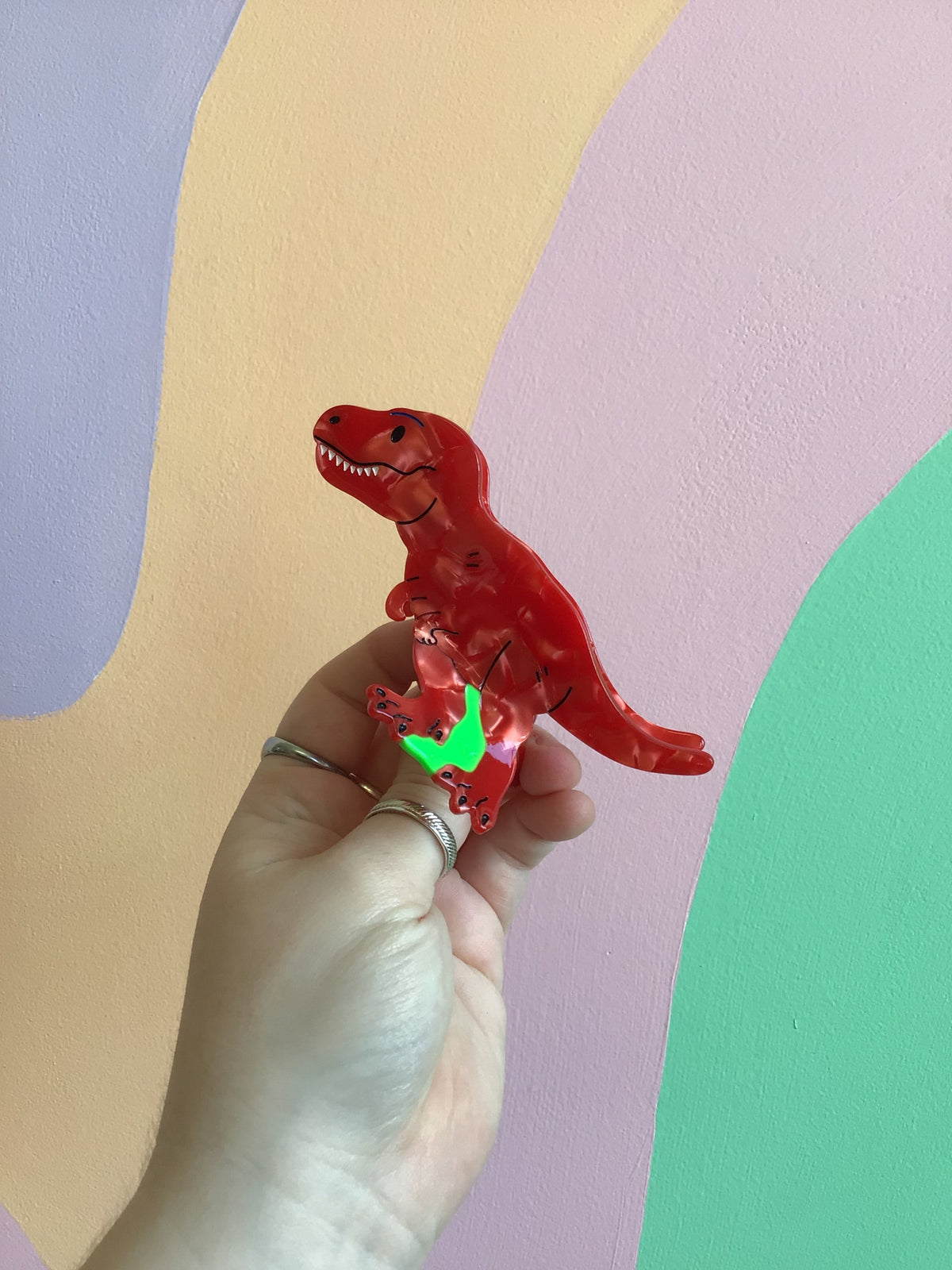 Red dinosaur hair claw with clear acrylic claws and green accessory detail