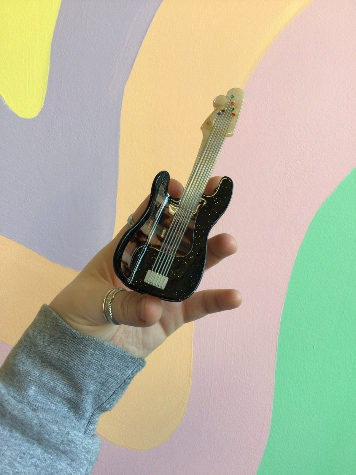 Black electric guitar hair claw with light strings and glossy highlights