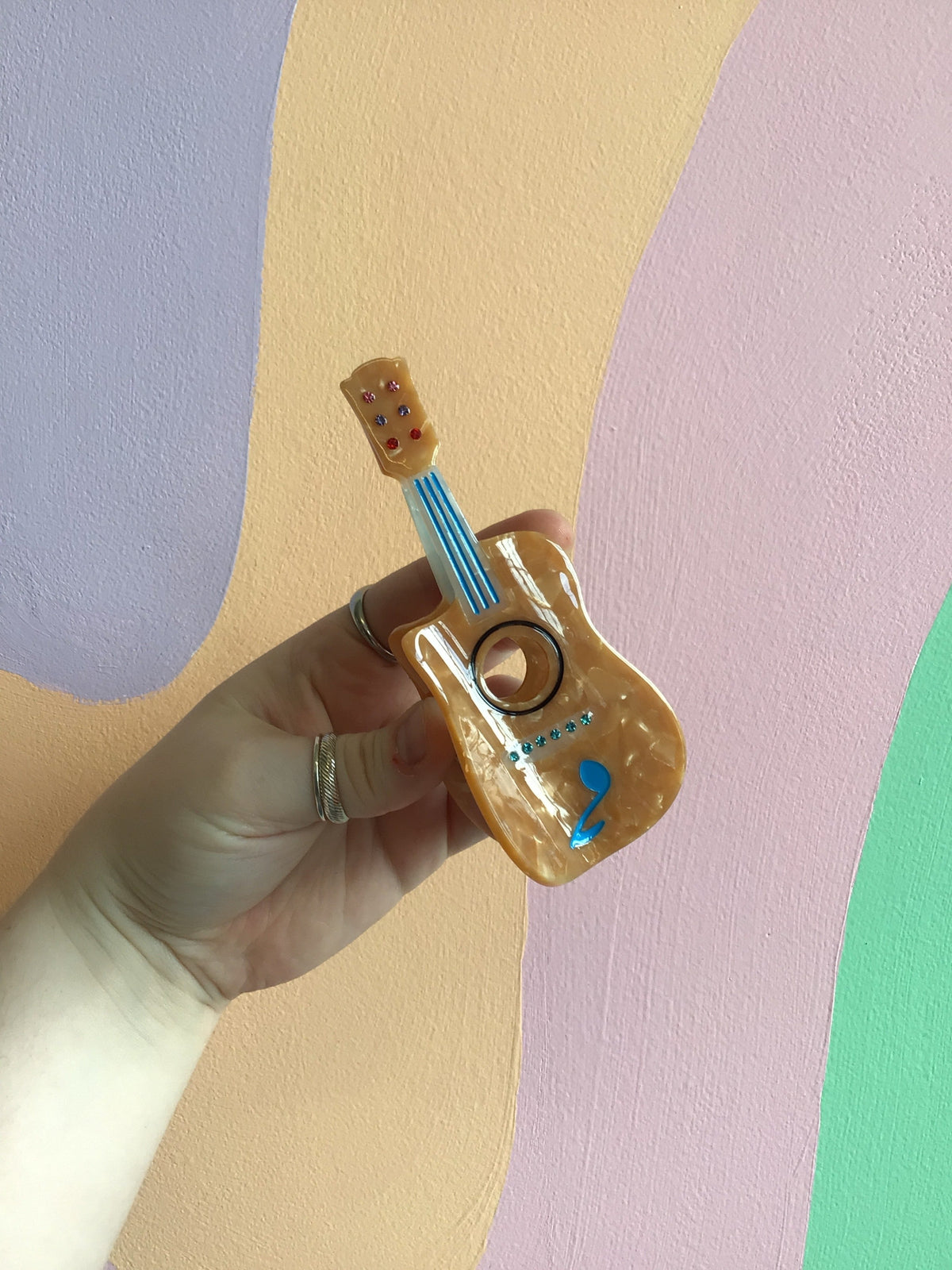 Tan violin-shaped hair claw with blue dot accents and glossy finish