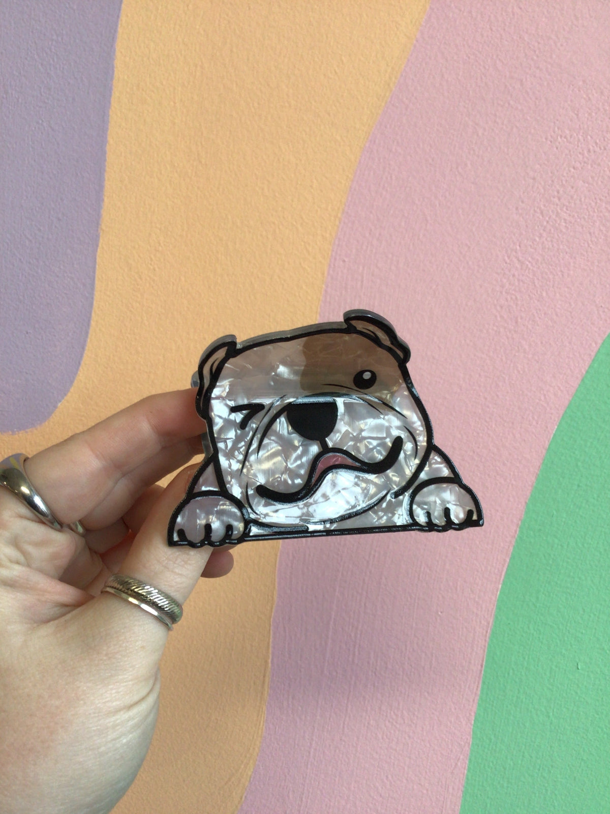 Brown-and-white bulldog hair claw with open-mouth smile, held in hand