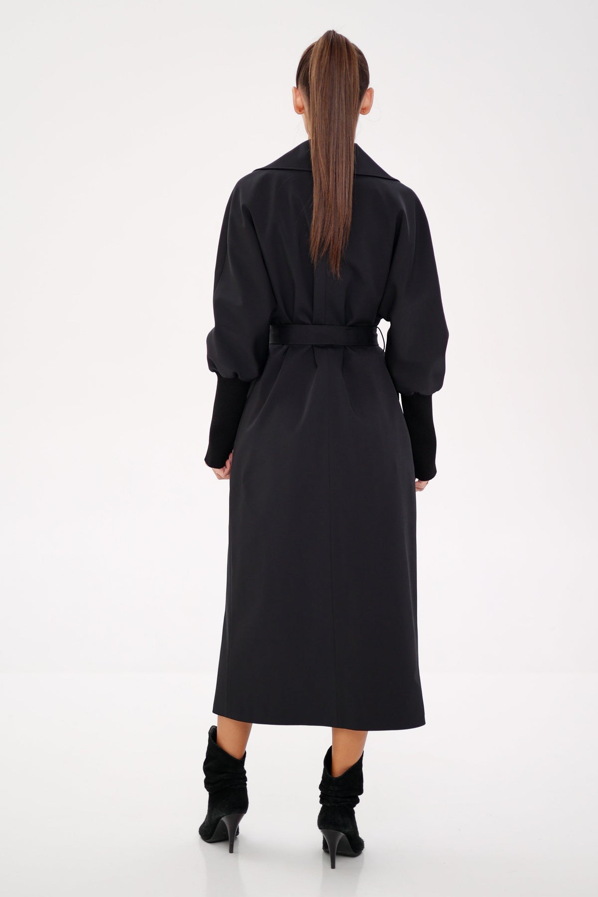 Back view of a black trench coat with a waist belt and long hem