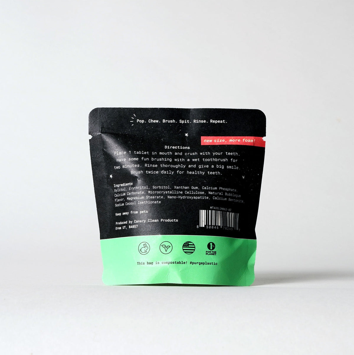 Back of a black and green toothpaste tablet pouch with directions and ingredients