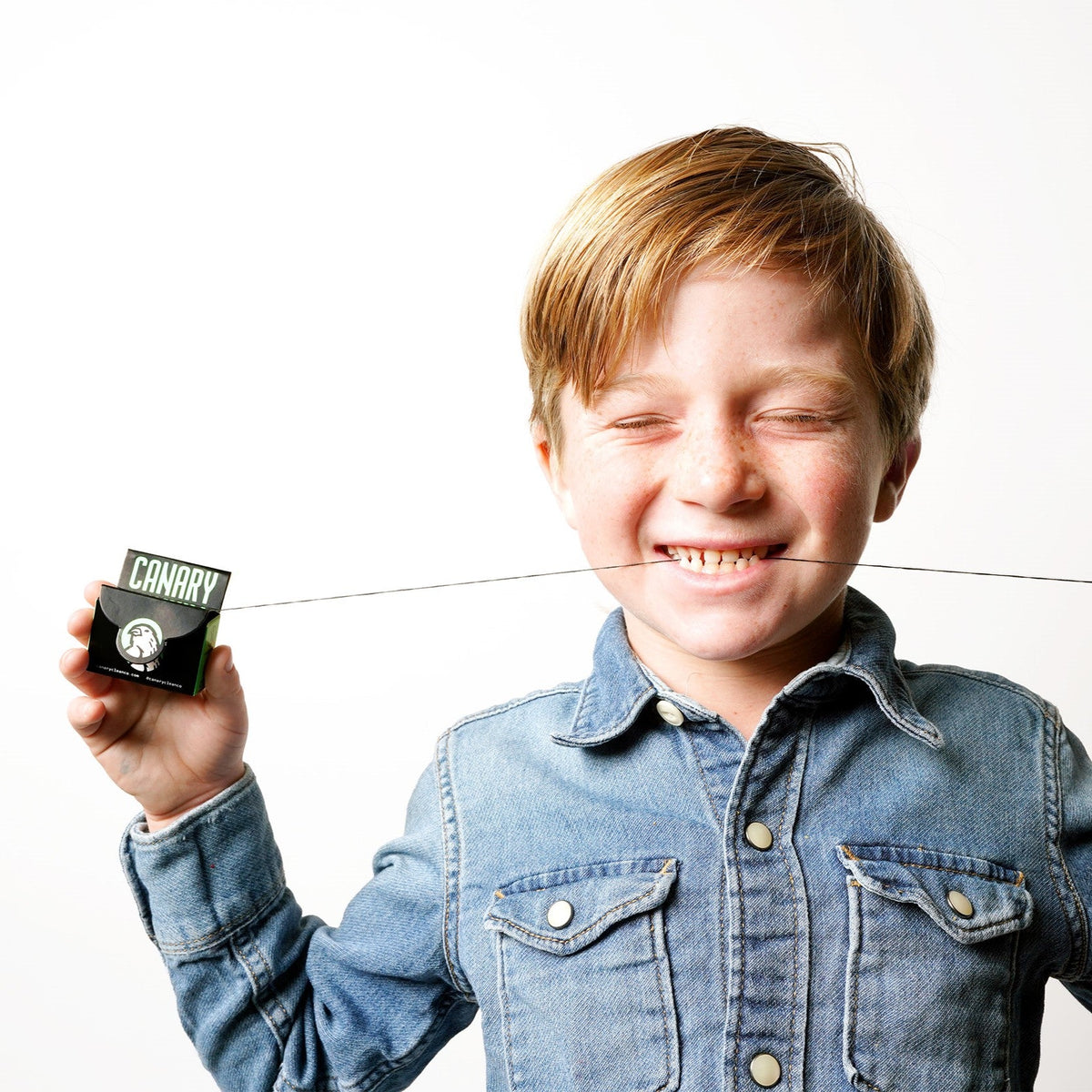 Vegan dental floss dispenser with floss stretched across a child's teeth