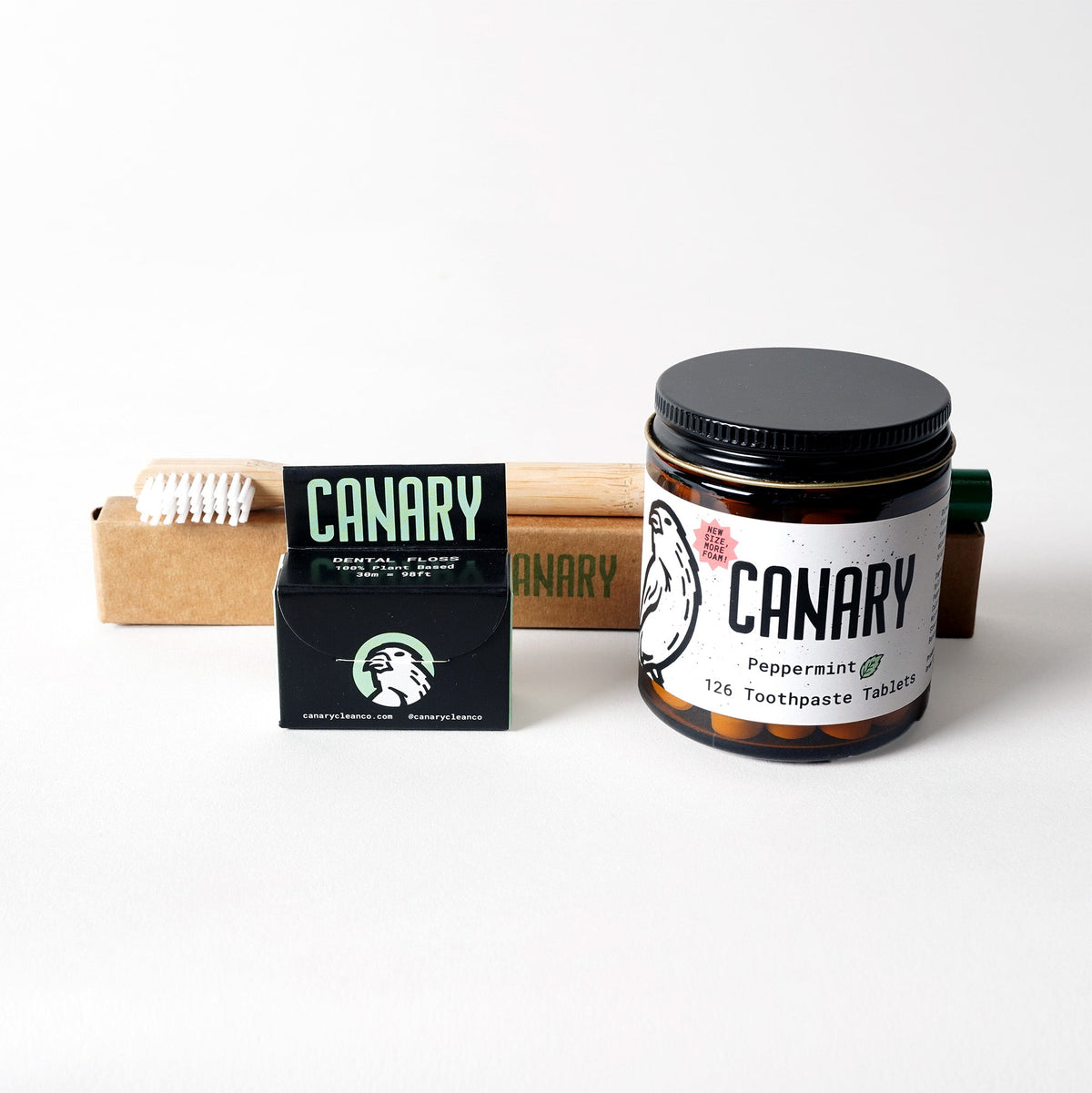 Peppermint toothpaste tablets, bamboo toothbrush, and vegan dental floss in cardboard packaging