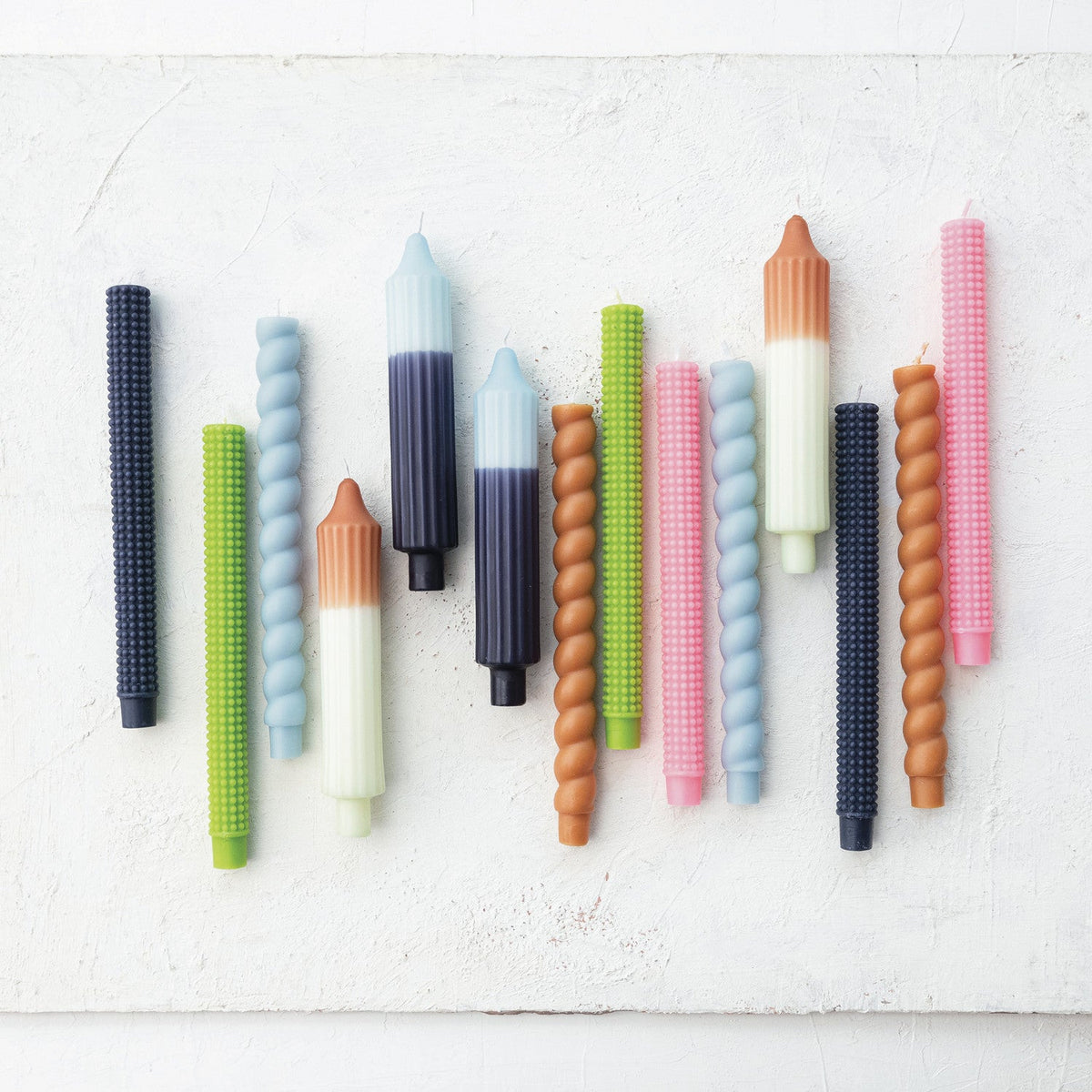 Assorted taper candles on wall, including blue two-tone pleated designs