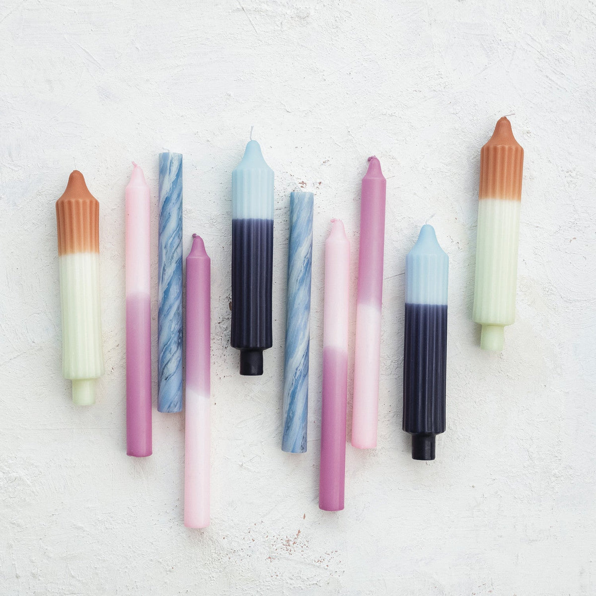 Assorted colored taper candles including blue two-tone pleated candle with dark base