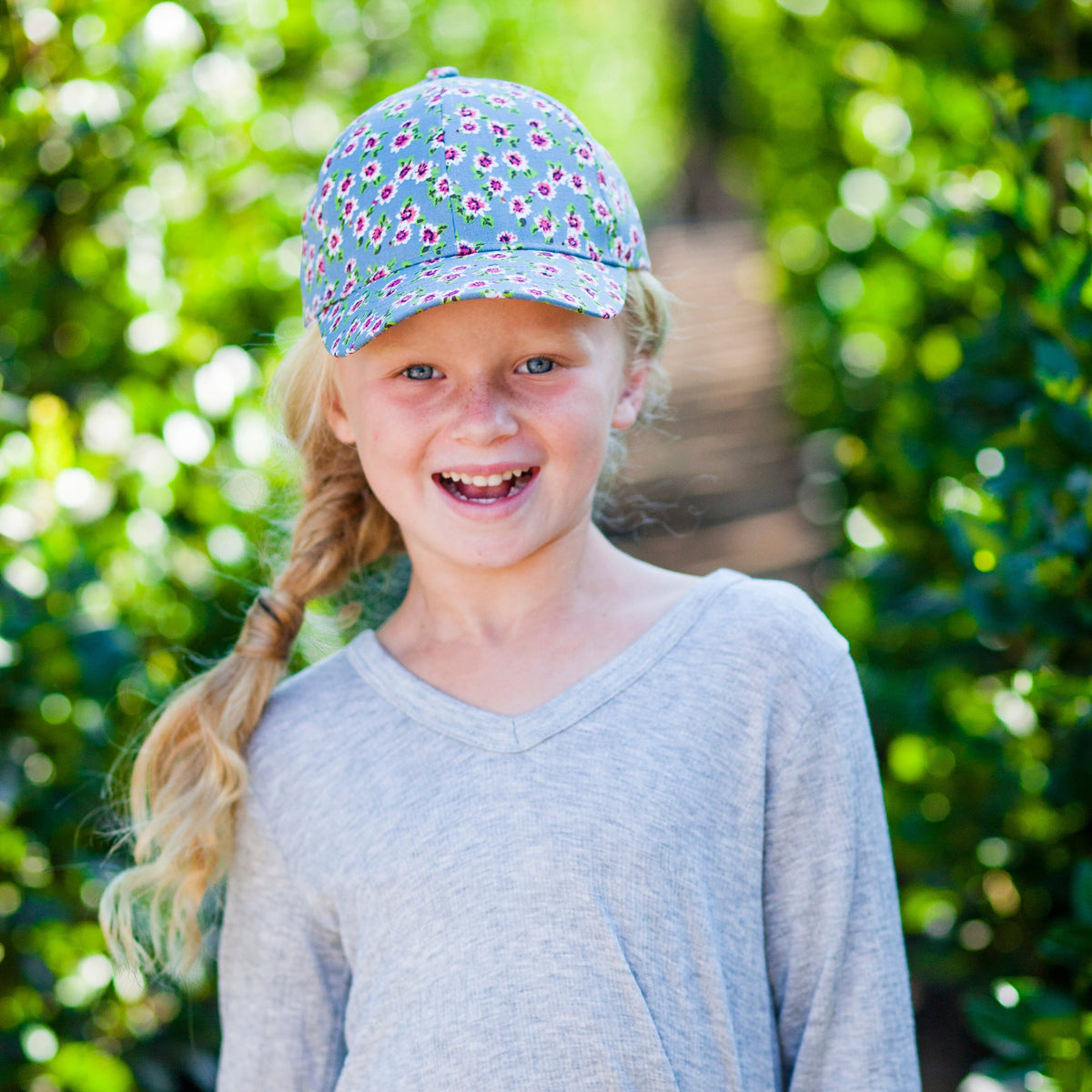 Girl wearing a blue floral baseball cap with small multicolor flowers.