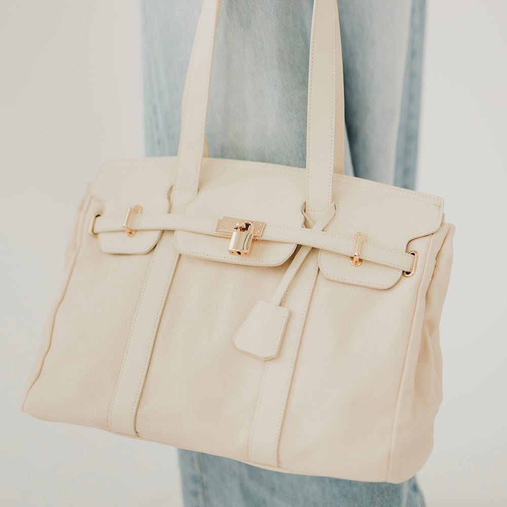 Cream canvas and vegan leather tote with front flap and buckle closure