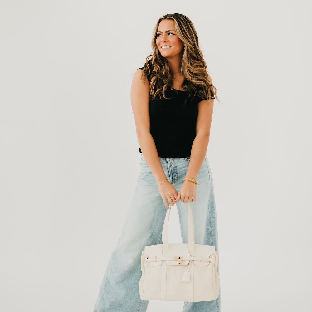 Cream canvas and vegan leather tote held by the top handles