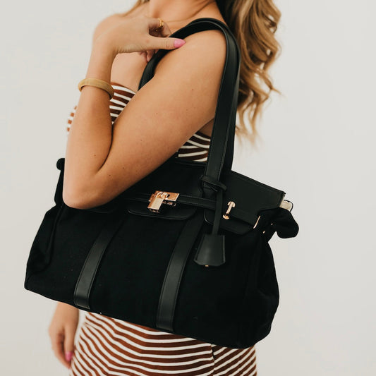 Black canvas and vegan leather tote with top handles and front buckle strap