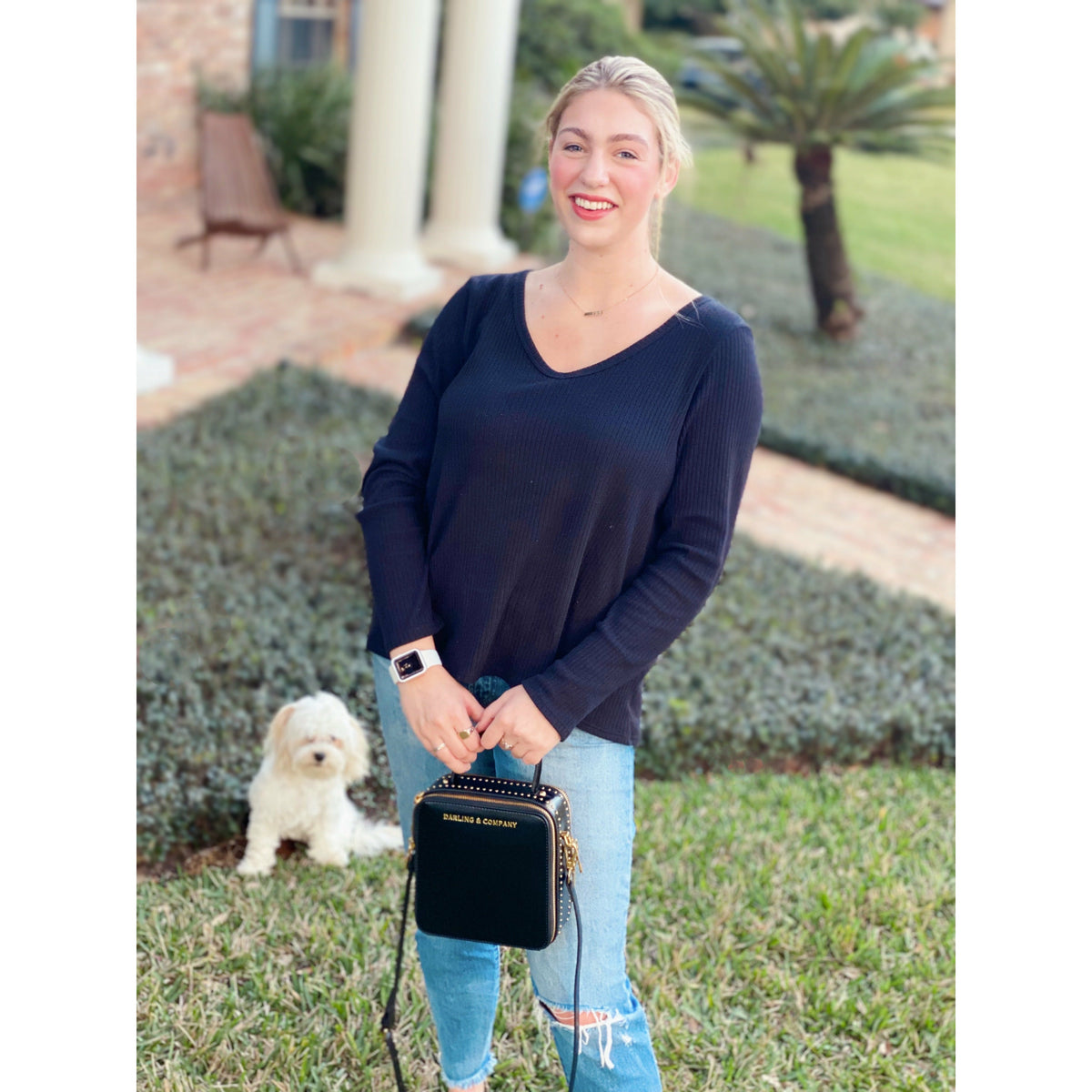 Woman holding a black mini handbag with top handle and gold hardware
