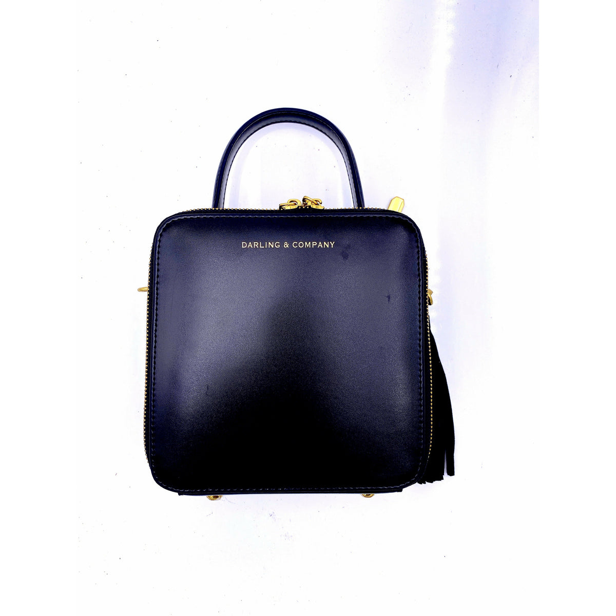 Black mini leather handbag with top handle and gold tassel
