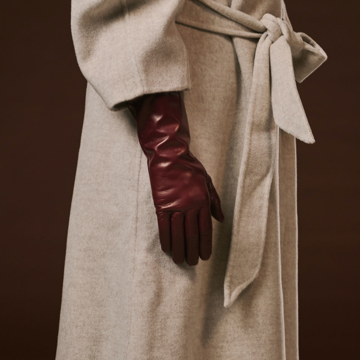 Cropped view of burgundy leather long gloves with cashmere-lined cuffs under sleeve.