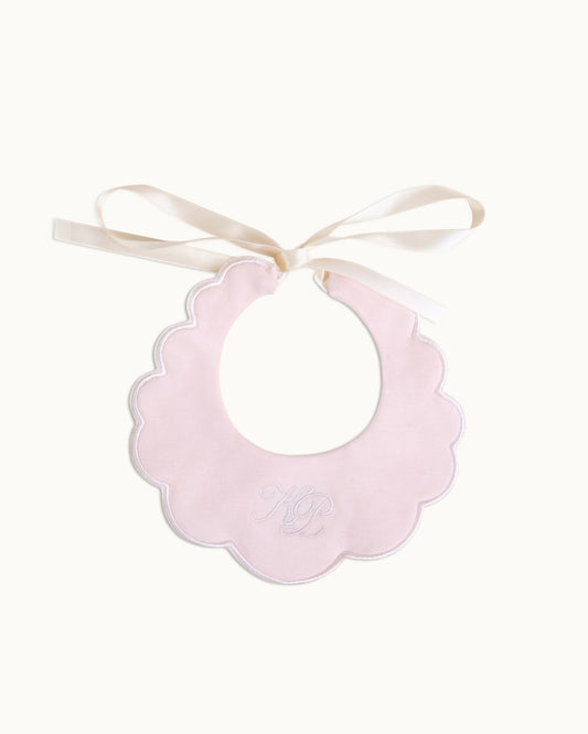 Light pink scalloped collar bib with ribbon ties and embroidered initials