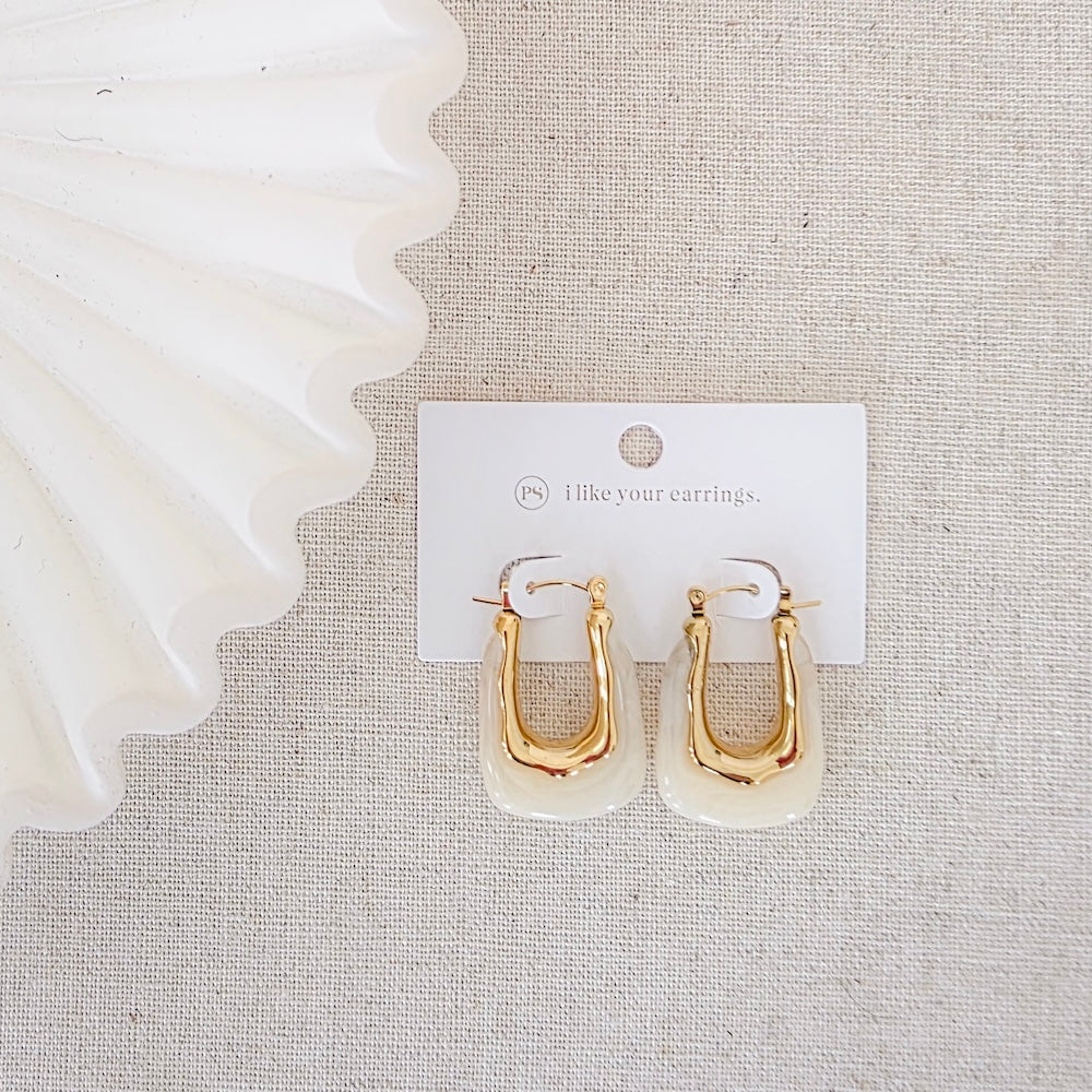 Gold-tone resin hoop earrings with white inner drop, packaged on display card