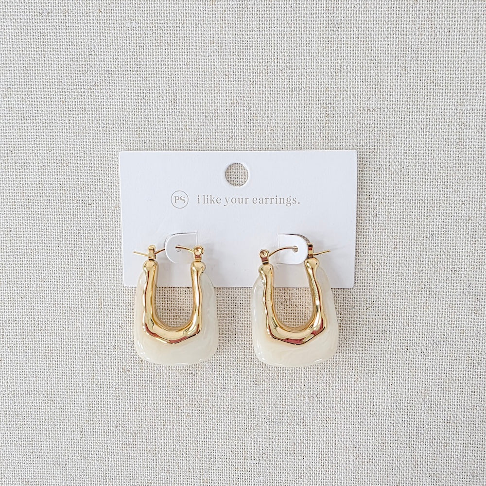 Pair of gold-tone resin hoop earrings with white inner drop, shown on card