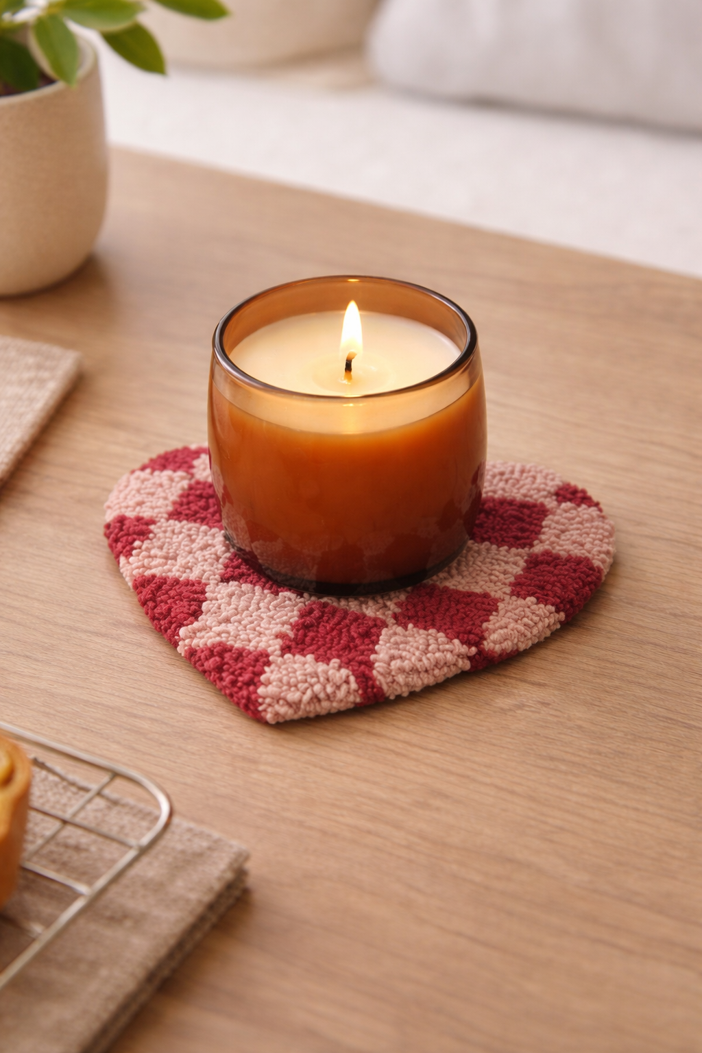Red checkered tufted cotton heart trivet under a candle.