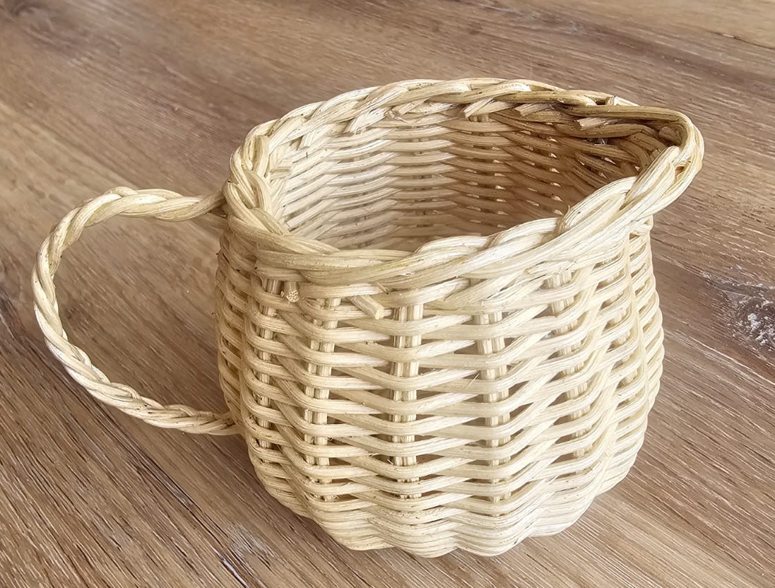 Close-up of a natural wicker cup with a braided handle