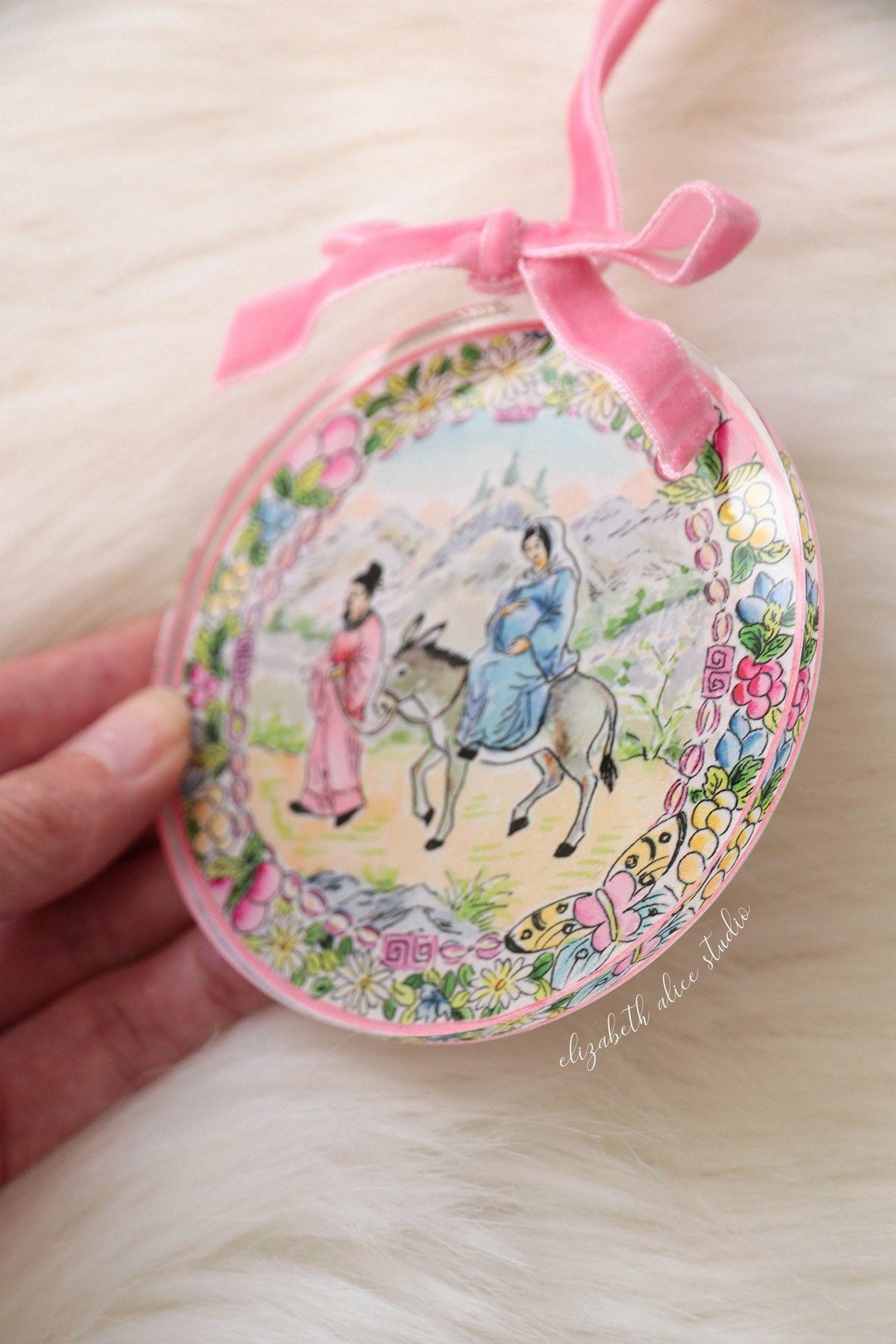 Close view of floral-bordered acrylic ornament showing Mary and Joseph on their journey