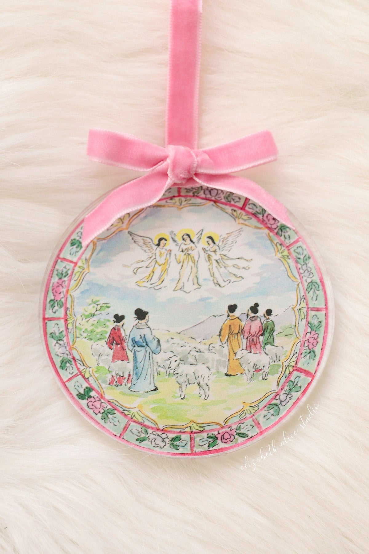 Round acrylic Christmas ornament with shepherds and angels scene, pink velvet bow and floral border