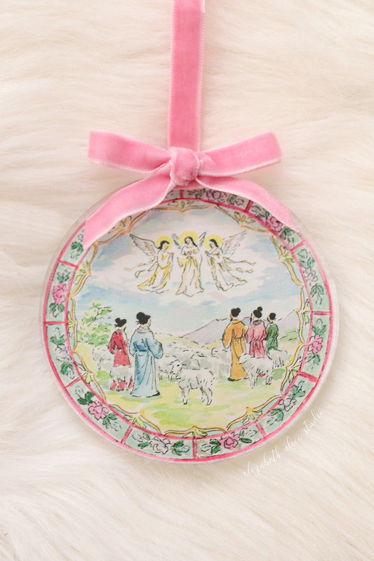 Round acrylic Christmas ornament with shepherds and angels scene, pink velvet bow and floral border
