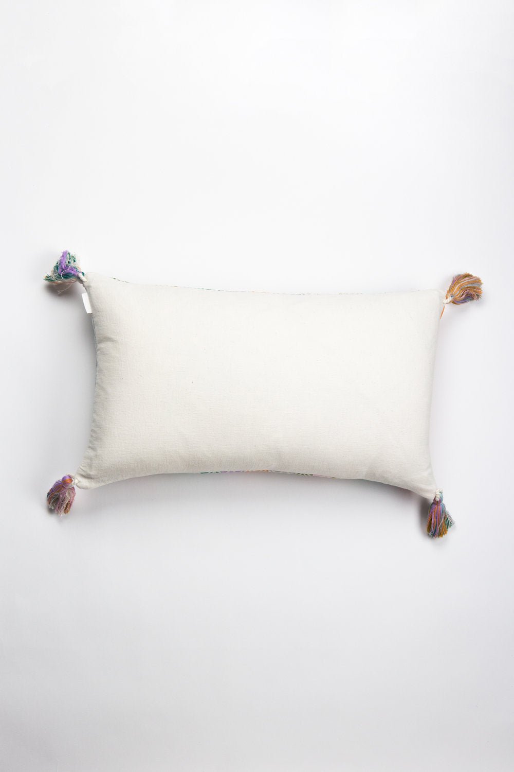 Plain white backing pillow with multicolor tassel corner ties