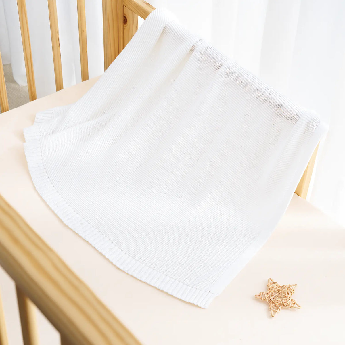 White knit baby blanket folded over, ribbed knit edge visible