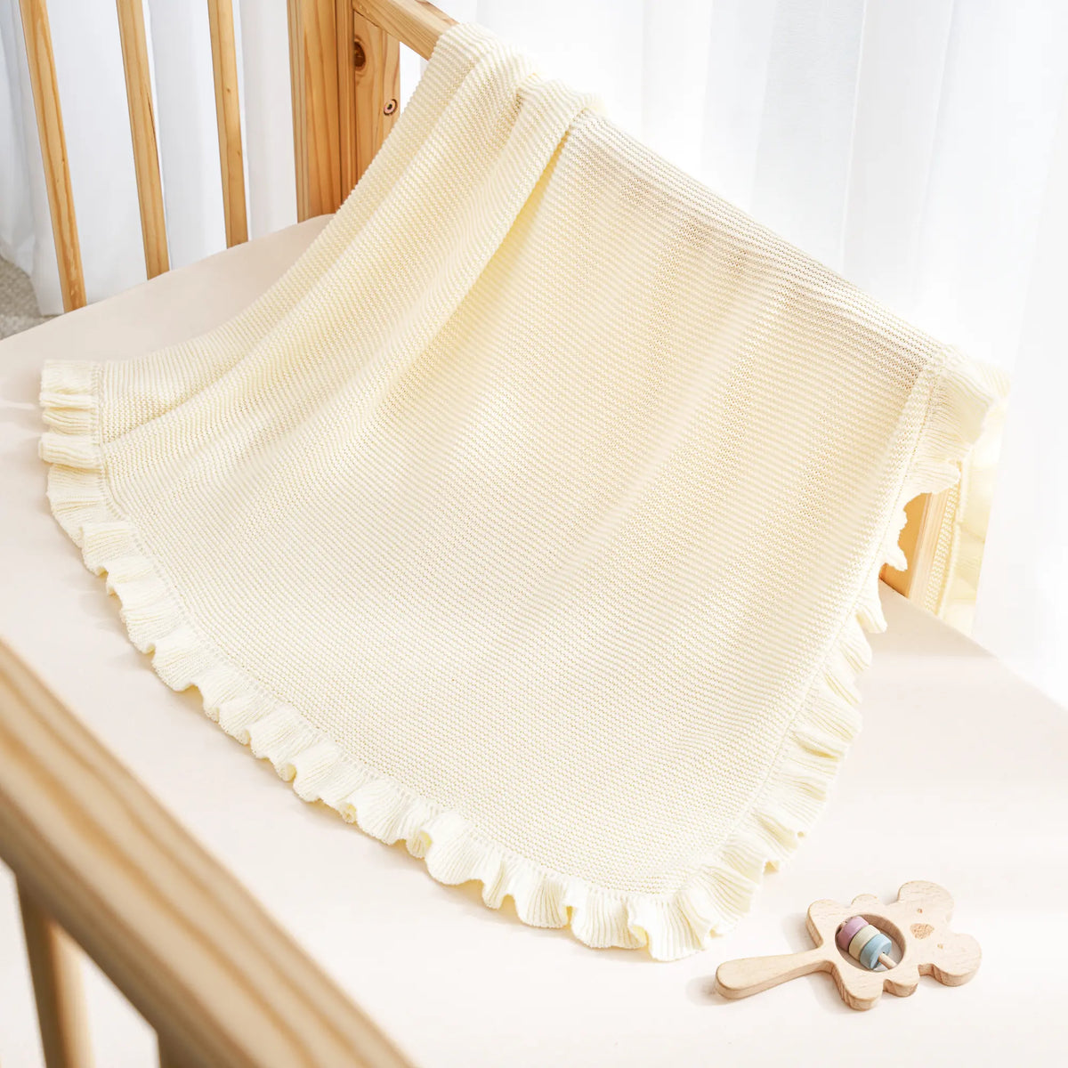 Cream ruffled edge knit baby blanket draped on a chair