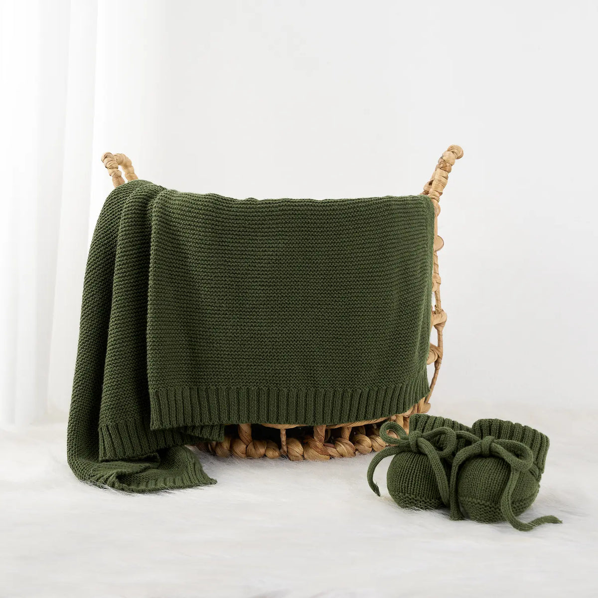 Forest green knit cotton baby blanket folded with woven loop ties at corners