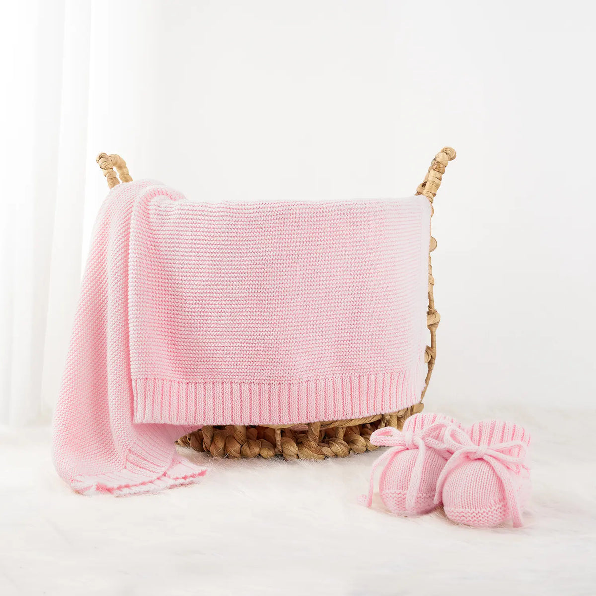 Pink knit cotton baby blanket spread out, showing ribbed hem