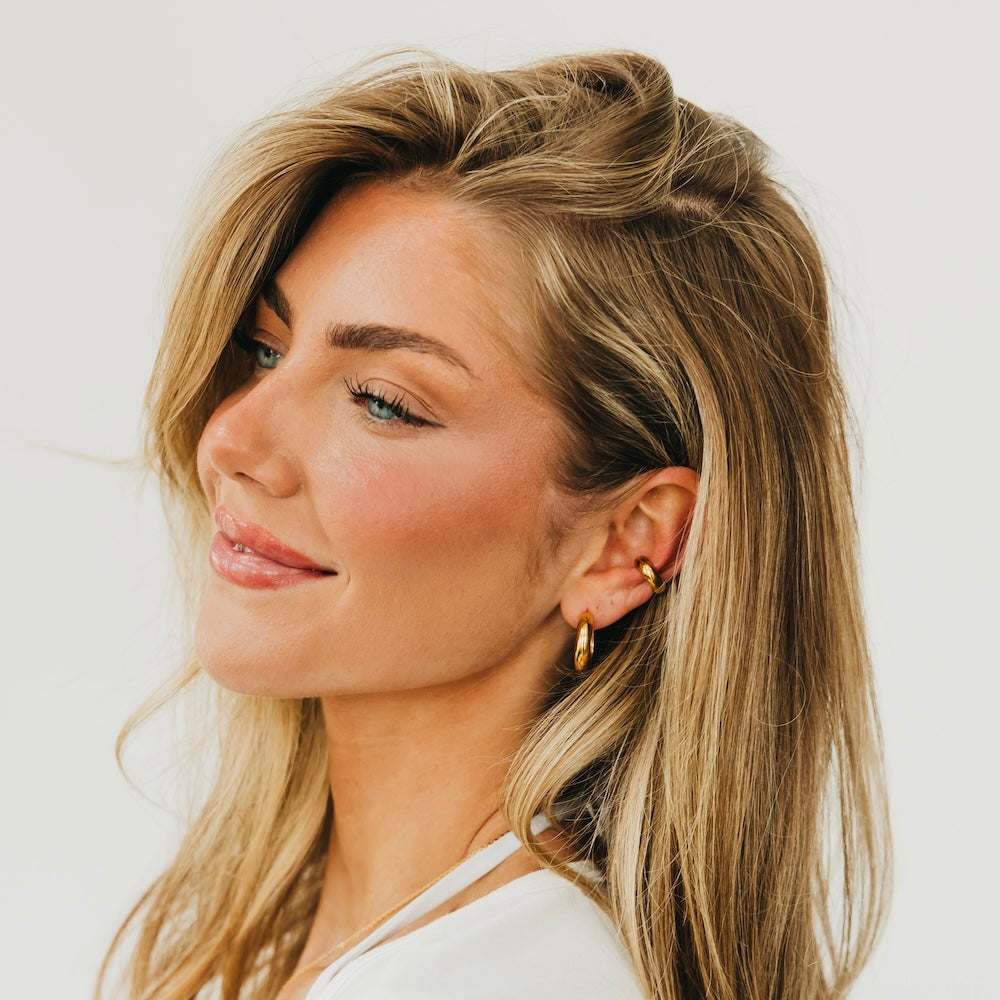 Gold conch ear cuffs and small hoop earrings, side view on model