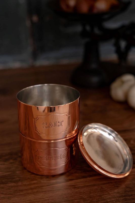 Copper salt and pepper cellar with open lid, engraved 'SALT' and 'PEPPER'.