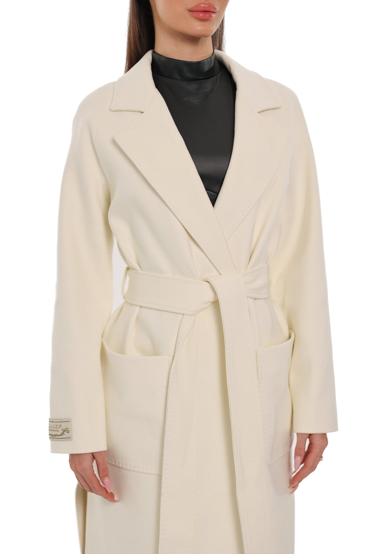 Ivory overcoat detail with notched lapels, tie belt and two patch pockets