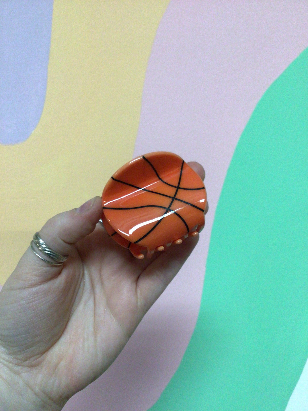 Basketball-shaped hair claw clip with black seam lines on orange