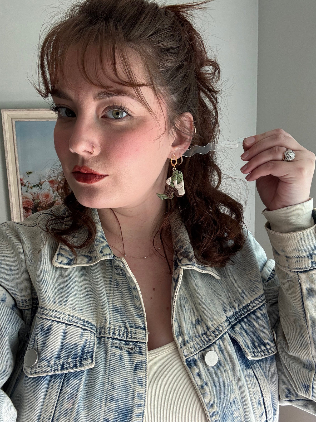 Dangling frog and toad charm earrings with gold hooks on a model