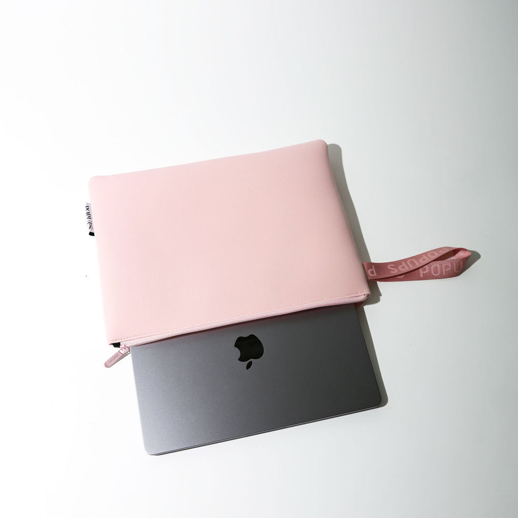 Pink laptop sleeve stacked on dark laptop sleeve, with zip and side ribbon strap